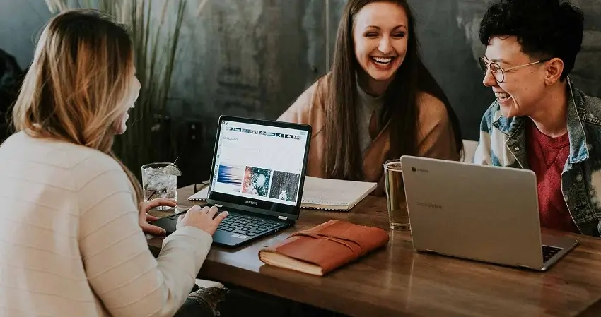 Personas reunidas riendose con sus laptops compartiendo ideas